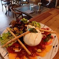 Planche de burrata et carpaccio dressée sur table en bois